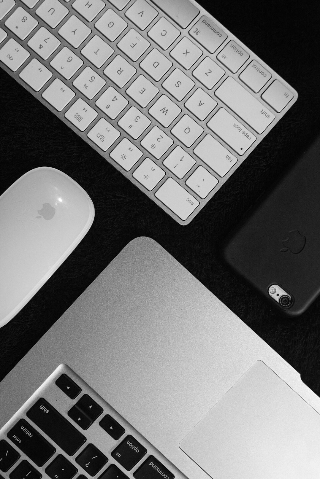 Person typing on a laptop keyboard near a phone and notebook